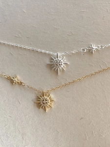 Macro shot of silver and gold starburst necklaces with shimmering pavé zircon details