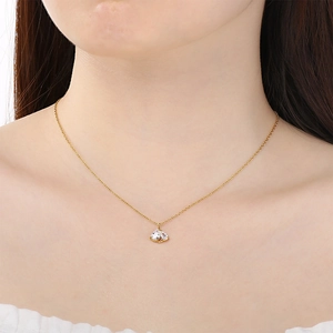 Close-up of golden necklace with clear heart-shaped crystal pendant on model's neck