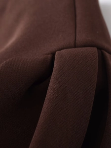 Macro shot of dark brown dress fabric showing detailed pleats and soft woven texture