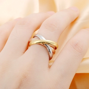 Close-up of interlocking three-tone titanium steel bands on golden silk fabric