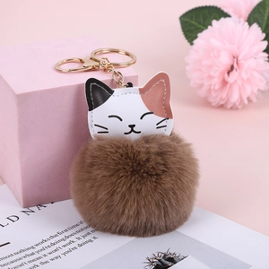Close-up of a cute lucky cat faux rabbit fur pompom keychain with a gold metal ring
