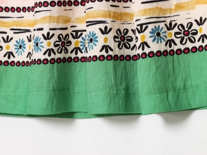 Close-up of vintage print fabric with green trim and ethnic floral patterns for women dress