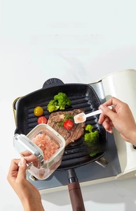 Macro detail of seasoning jar with measuring spoon adding salt to steak in a pan
