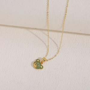 Macro view of gold pendant necklace featuring a green zircon bear head with fine gold chain