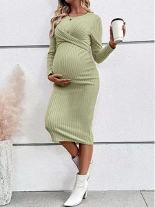 Close-up of sage green ribbed knit maternity dress with twist knot detail and long sleeves