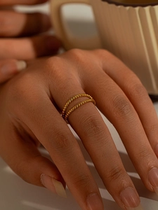 Double-layered gold bead ring design shown on finger with minimalist aesthetic
