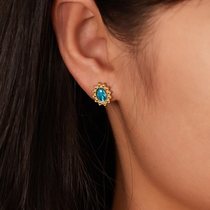 Vintage gold-plated oval stud earrings with blue gemstone worn by a model