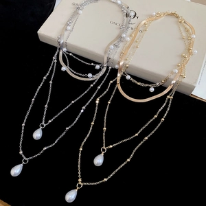 Detail view of gold and silver layered necklaces with water drop pearls and metal chains