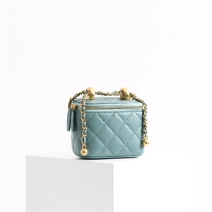 Detailed close-up of teal diamond quilted leather bag with gold ball chain strap