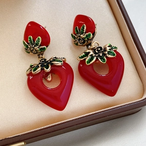 Makro-Detail von Vintage-Herz-Ohrringen in Erdbeerrot mit Goldmetall und grünem Emaille
