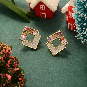 Macro shot of gold square earrings with colorful gemstones and pavé crystals on green felt