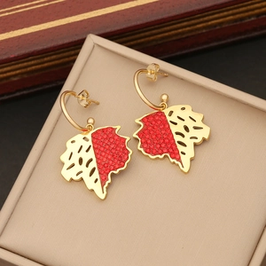 Macro view of gold leaf earrings with red rhinestones and intricate hollow metalwork