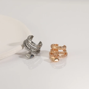 Detail of French vintage heart ear cuff with gold and silver chain textures and rhinestones