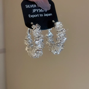 Macro shot of 925 silver hoop earrings featuring baguette-cut cubic zirconia in a cluster