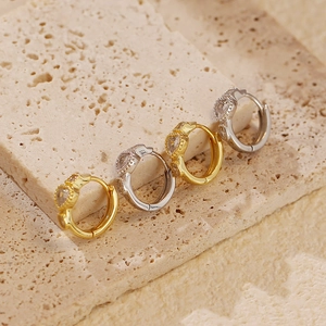 Macro shot of silver and gold heart huggie earrings with cubic zirconia inlay on stone