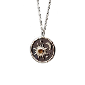 Detailed macro shot of vintage silver sun and moon pendant necklace with amber gemstone