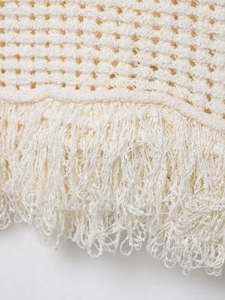 Détail de la texture en maille crochet blanc cassé avec franges douces et motifs ajourés