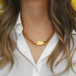 Close-up of a gold chunky chain necklace with a rectangular metal plate on a model