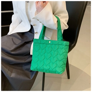 Detail of green quilted heart pattern on nylon tote bag with metallic snap closure