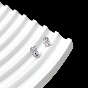 Detailed view of silver screw-back stud earrings with floral clover backings on white tray