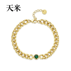 Macro view of gold curb chain bracelet featuring a round green zircon center and lobster clasp