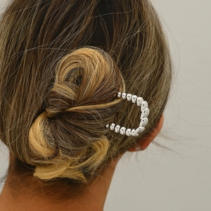 Macro shot of silver U-shaped metal hair pin with beaded texture in an elegant bun