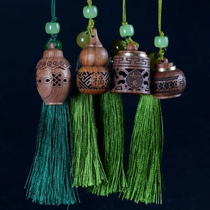 Detail of hand-carved sandalwood pendants with green silk tassels on dark blue background
