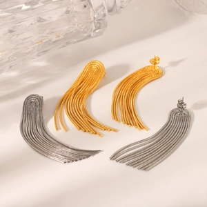 Macro detail of cascading gold and silver fringe chain earrings on a beige surface