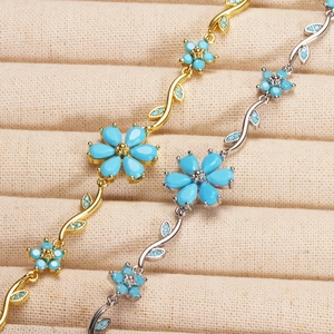 Detail of gold and silver plated flower bracelets with blue petals and leaf chain links