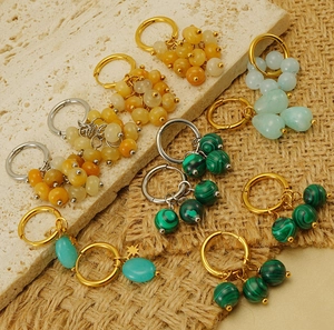 Close-up of 18k gold earrings with malachite and gemstones on natural stone background