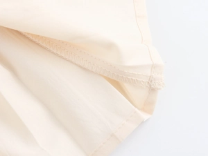 Dettaglio del tessuto in tweed beige che mostra le cuciture dell'orlo e la trama premium