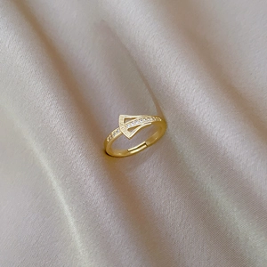 Macro detail of S925 silver gold-plated ring with zircons on champagne silk fabric
