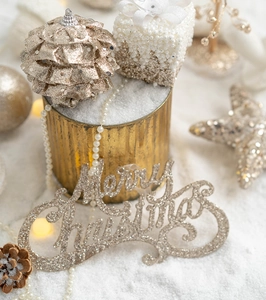 Macro detail of golden Merry Christmas sign with pine cones and white snowy ornaments