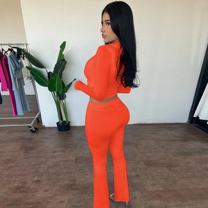 Side view of orange two-piece slim fit set with long sleeve crop top and flared trousers