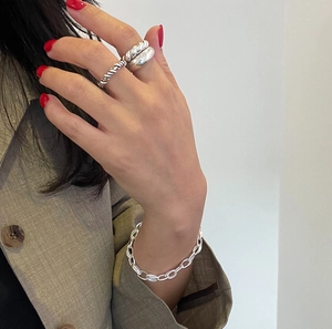 Detail of silver chain bracelet and textured rings on a model with red nails