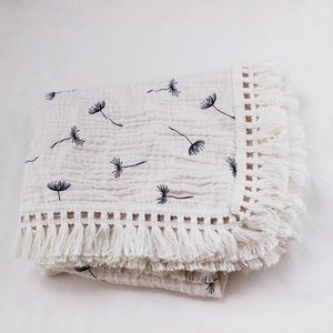 Detail of embroidered dandelion pattern on soft muslin cotton baby blanket with tassels