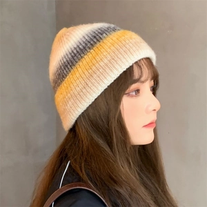 Detail of warm knit beanie featuring yellow, cream, and grey gradient striped texture