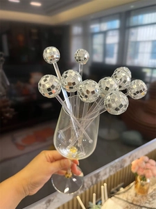 Detail shot of 3cm silver disco ball cocktail stirrers in a glass for party drinks