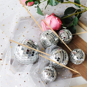 Close-up of seven silver disco ball cake toppers with mirror finish and wooden sticks