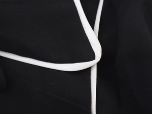 Gros plan détaillé du passepoil blanc contrasté sur le tissu en mousseline noire de la robe