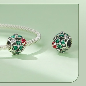 Macro shot of silver four-leaf clover charm with red ladybug and green enamel detail