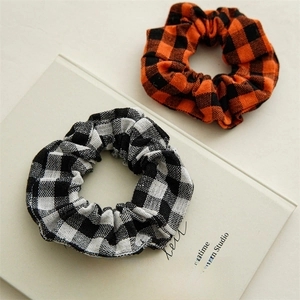 Detailed close-up of orange and white plaid scrunchies on a white book surface