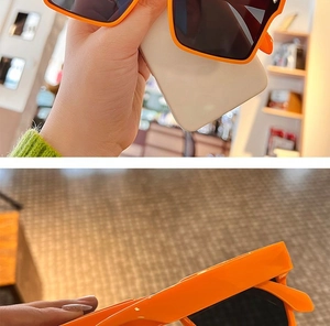 Detail view of bold orange square resin sunglasses featuring dark UV protection lenses