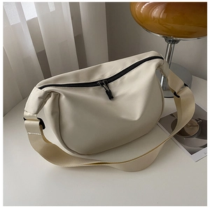 Detail of minimalist beige crescent bag showing the nylon texture and double zipper feature