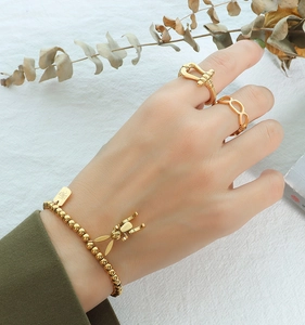 Nahaufnahme von goldenem Perlenarmband mit Hasenanhänger und geometrischen Ringen