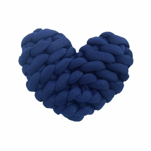 Detailed view of dark blue hand-knitted heart pillow with chunky cotton yarn texture