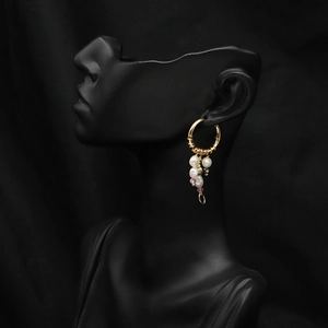 Detailed shot of gold baroque pearl hoop earrings with colored beads on a model