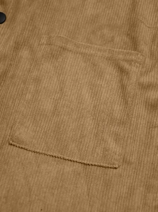 Detail shot of brown corduroy shirt showing pocket stitching and dark button texture