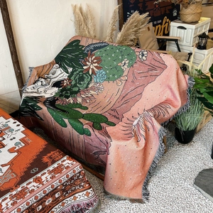 Close-up of bohemian woven blanket with fringe and cactus skull patterns on a chair