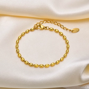 Detailed macro view of gold ball chain bracelet with K18 engraving on smooth satin